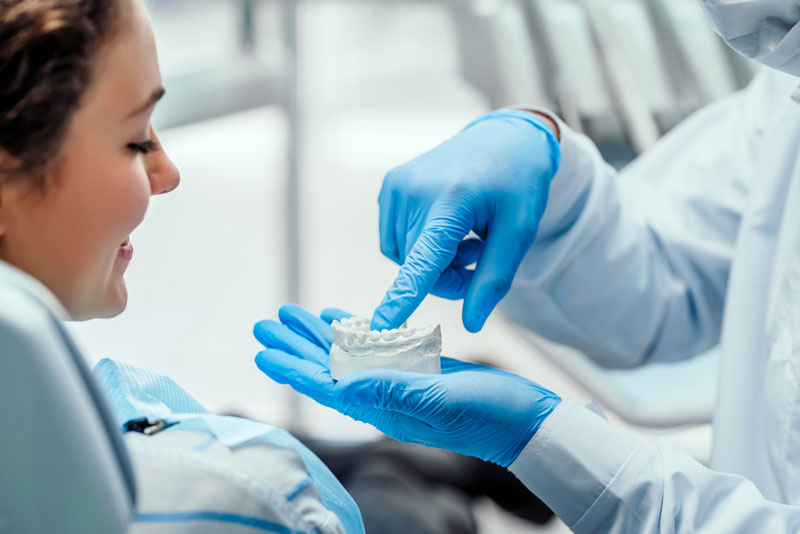 a doctor showing an implant patient a dental implant model.