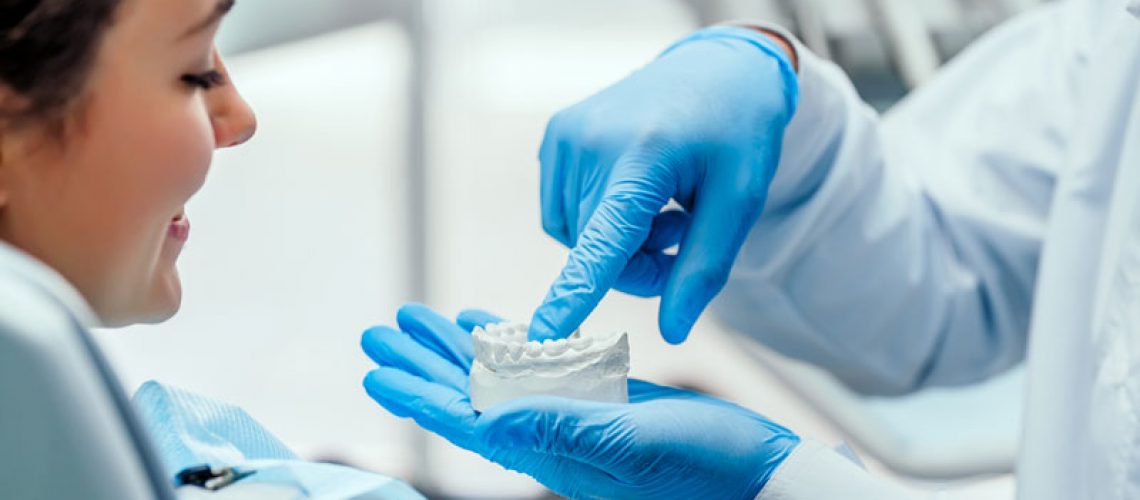 a doctor showing an implant patient a dental implant model.