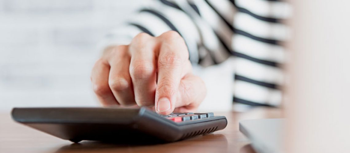 image of a patient using a calculator to figure out the cost of getting dental implants